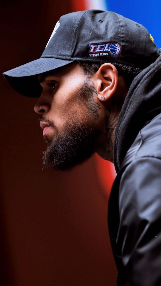 a close up of a person wearing a hat and ear piercings, looking off to the side