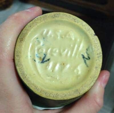 a person holding a small jar with writing on it's lid in their hand