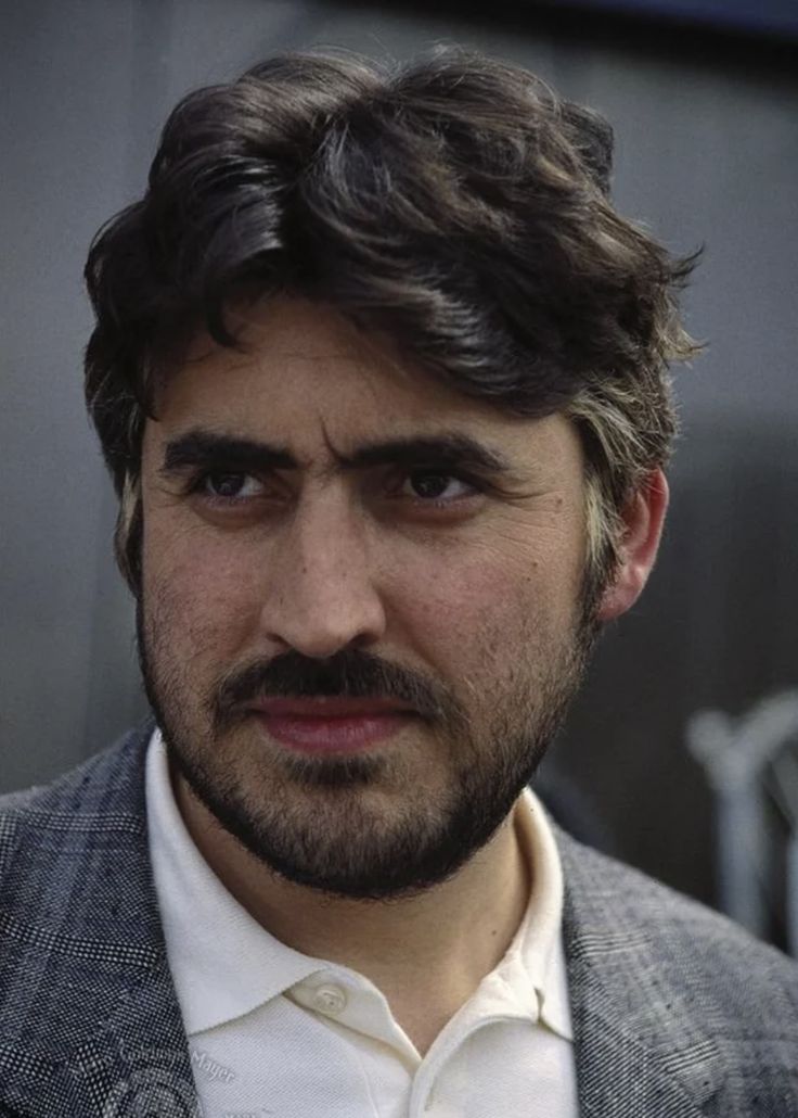 a close up of a person wearing a suit and tie with a goatee on