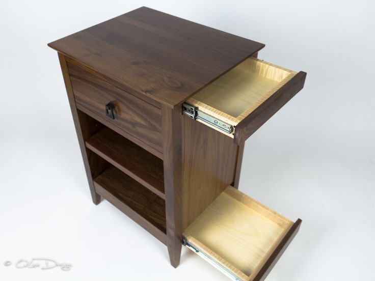 a wooden cabinet with two open shelves on one side and a drawer on the other