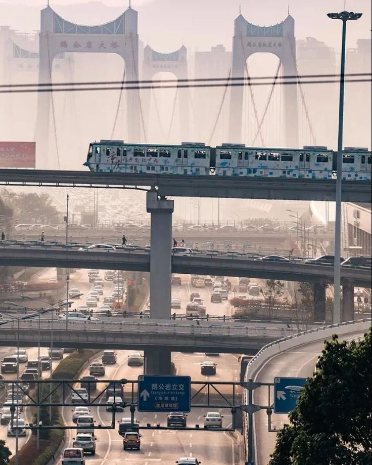 a train is going over a bridge with cars on the road in front of it