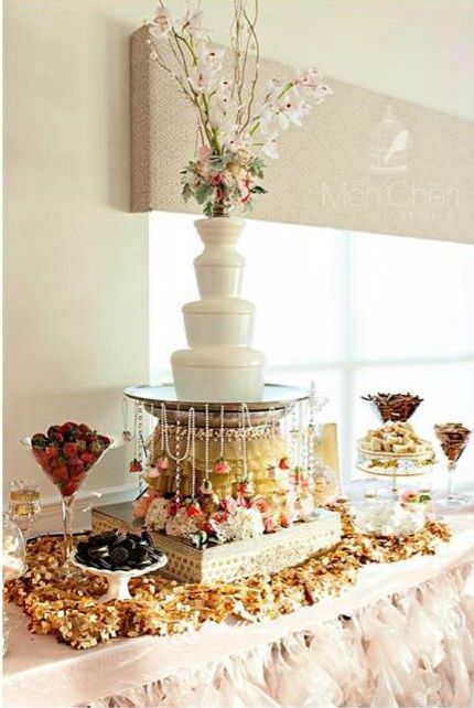 a table topped with lots of food and desserts next to a tall vase filled with flowers