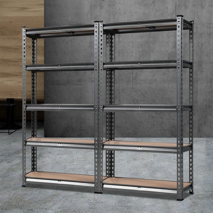 two metal shelvings with wooden shelves in front of a concrete wall and floor