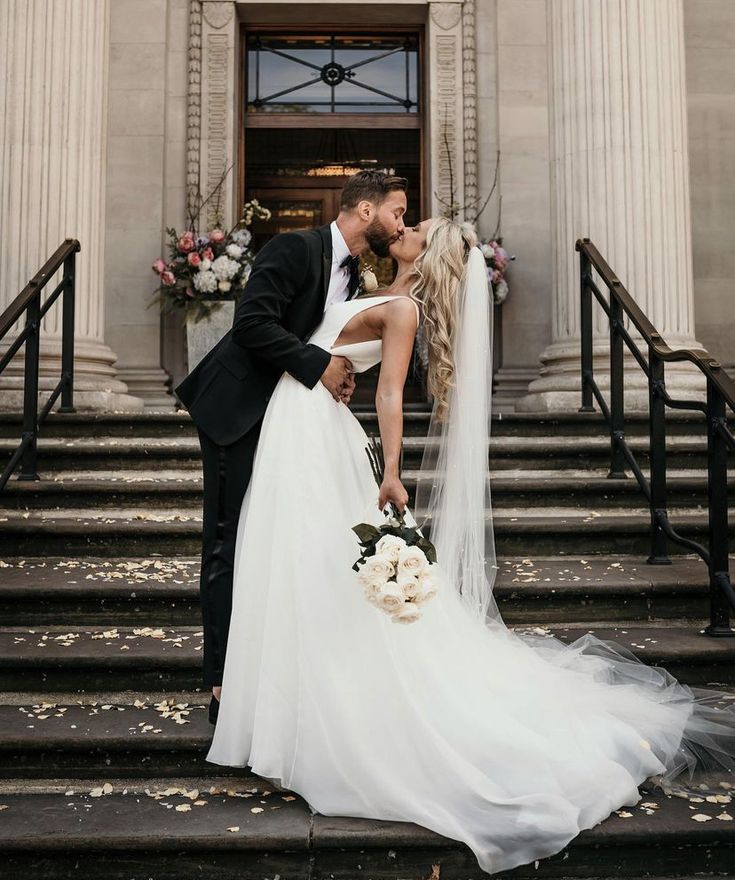 a bride and groom kissing in front of a building