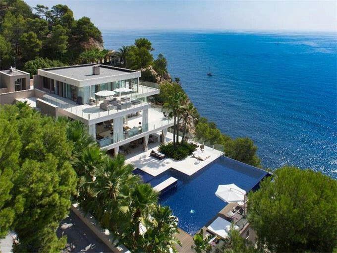 an aerial view of a large house on the water's edge with trees surrounding it