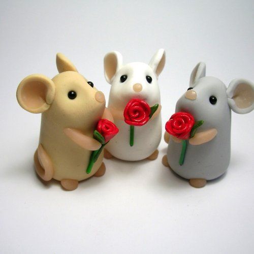 three ceramic mice with flowers in their hands on a white surface, one is holding a red rose and the other two are smaller