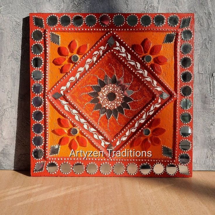 an orange and black decorative tile on a wooden surface with the words aryzeh traditionals written below it