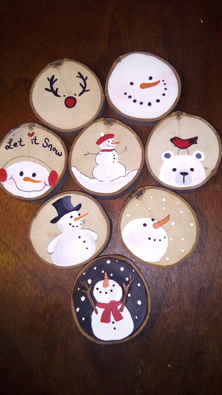 six snowmen painted on wooden plates sitting on top of a wood table next to each other