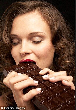 a woman eating a chocolate bar with her eyes closed