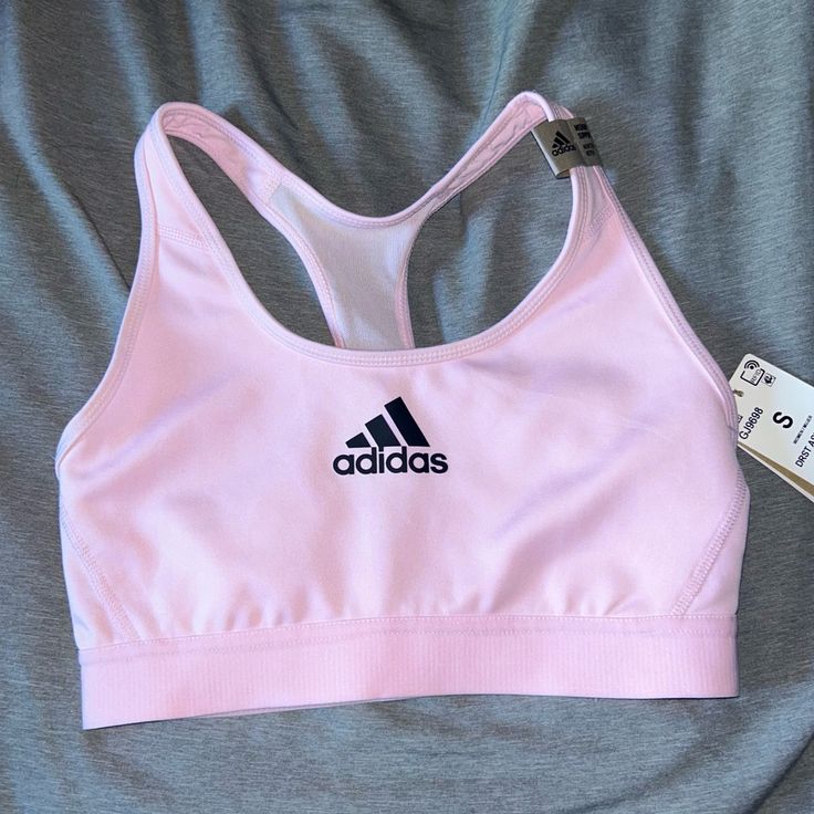 a pink sports bra with adidas logo on it and a pair of scissors next to it