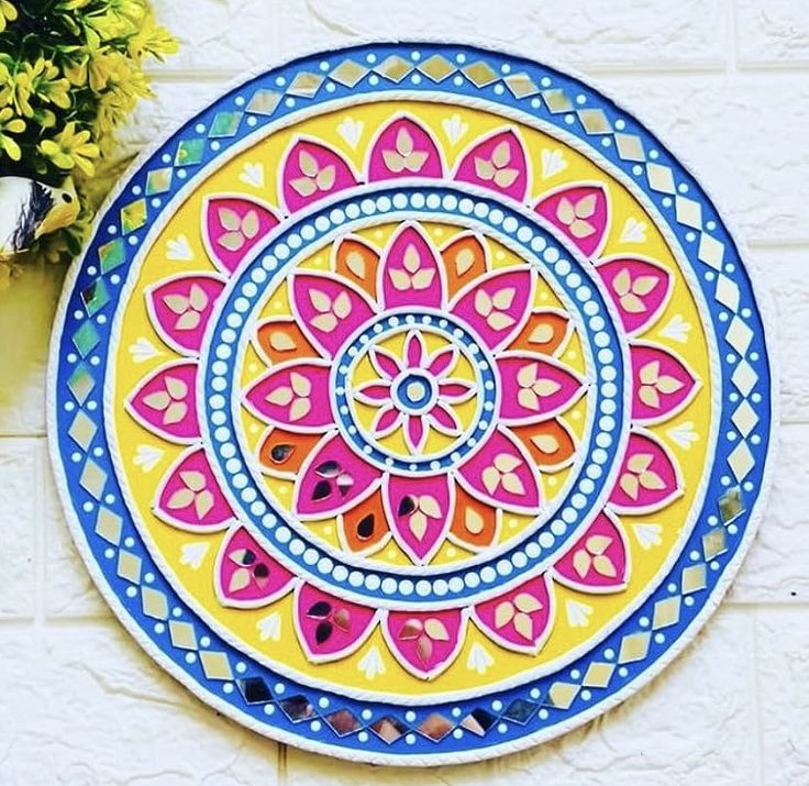 a colorful painted plate sitting on top of a wall next to a potted plant