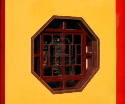 a red and yellow wall with a window in the middle that has bars on it