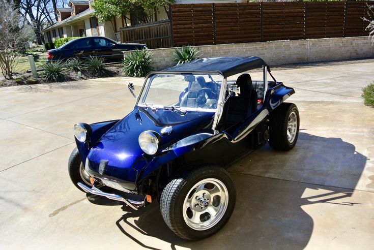 a blue and black buggy parked in front of a house next to a driveway