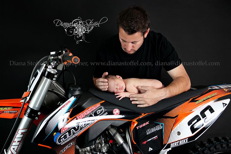 a man holding a baby on top of a dirt bike with an orange and black background