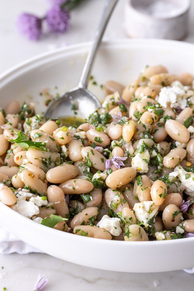 a white bowl filled with beans and feta cheese