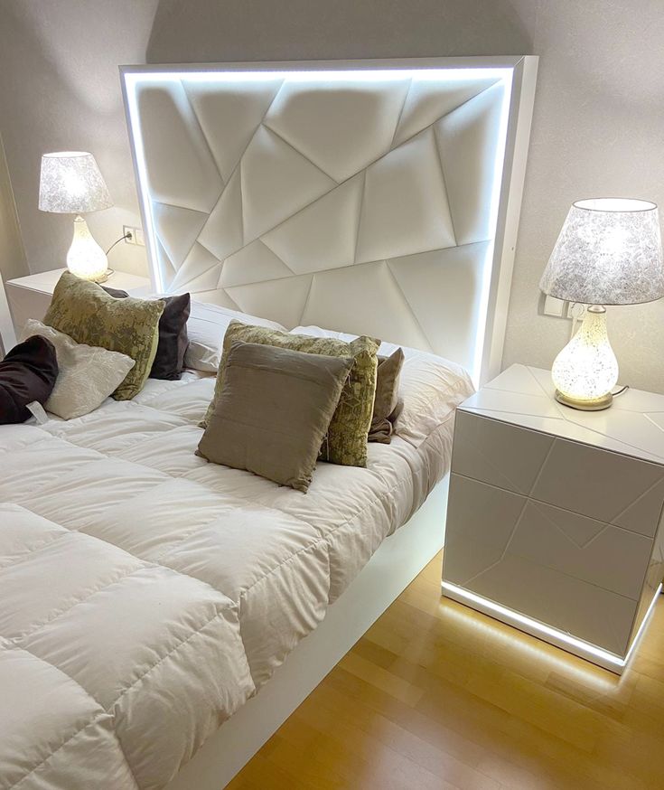 a white bed with pillows and lamps on either side