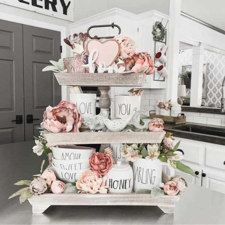 three tiered trays filled with coffee cups and flowers on top of a kitchen counter