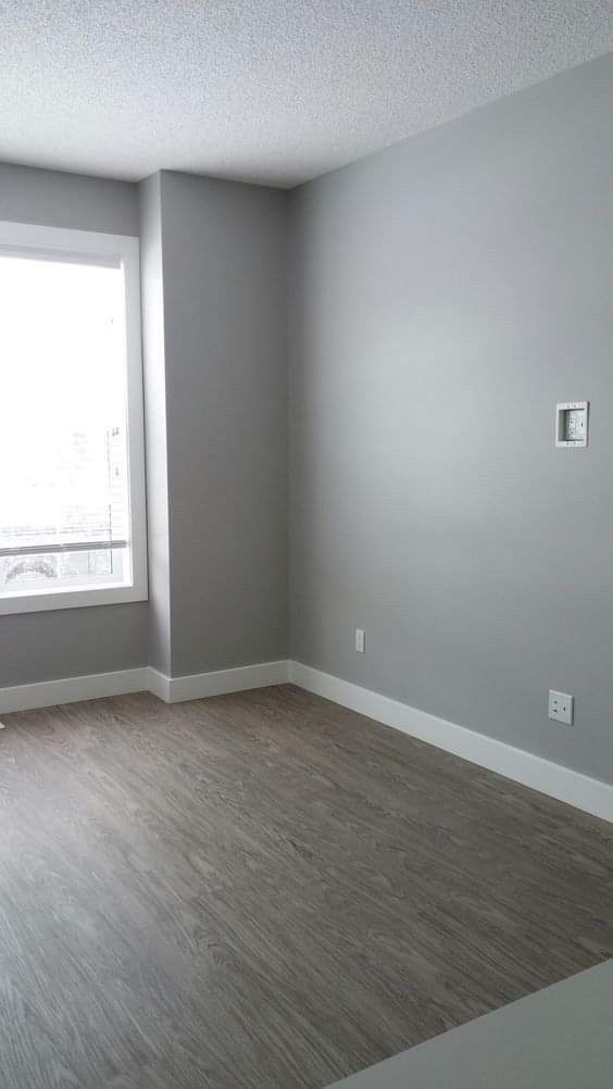 an empty room with wood flooring and gray walls in the corner, looking out to the street