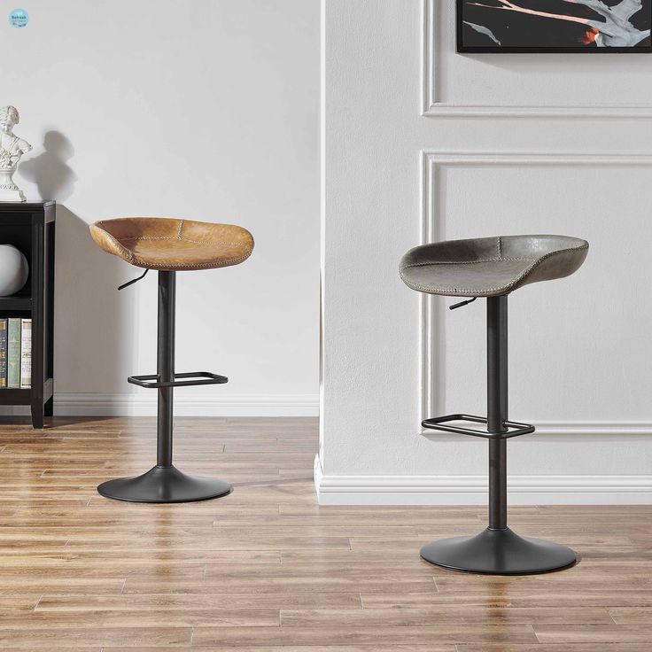 two modern barstools sit in front of a white wall and hardwood flooring