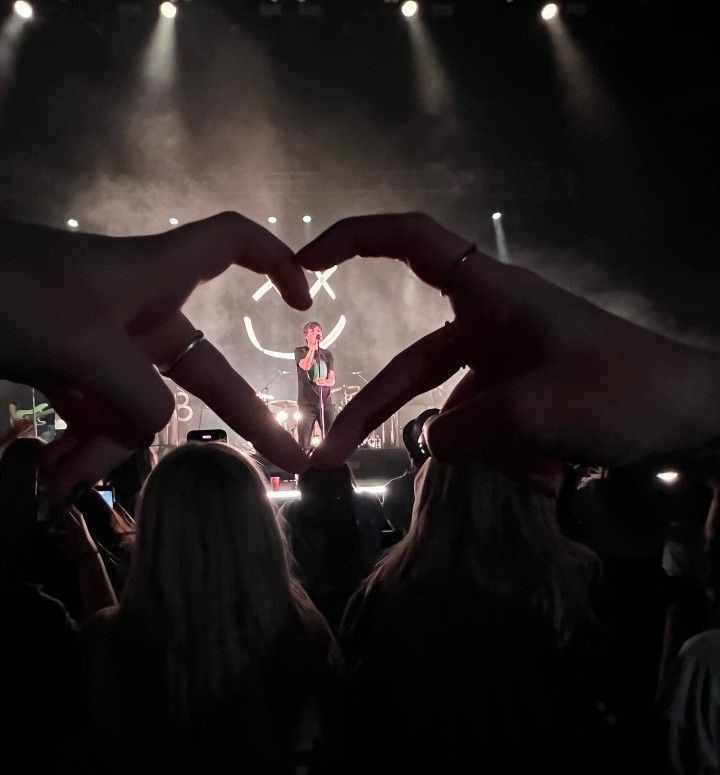 two hands making a heart shape at a concert