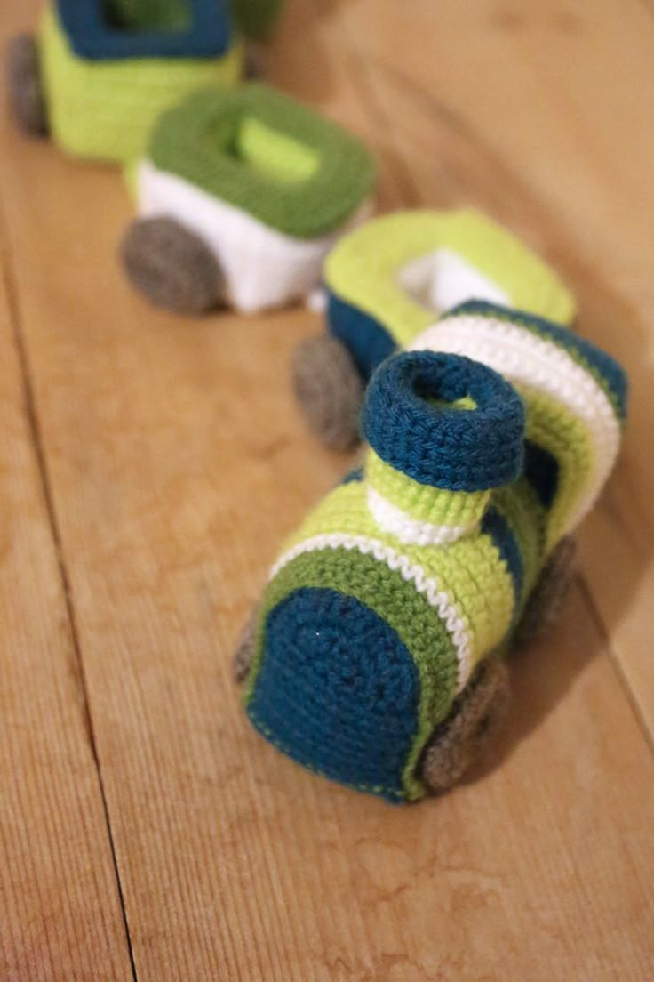 two knitted toy cars sitting on top of a wooden floor next to each other