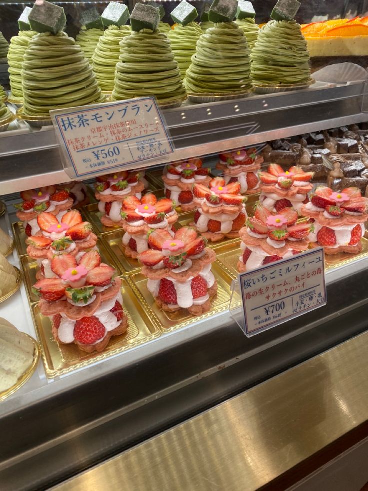 there are many desserts on display in the case at this store, including strawberries and bananas