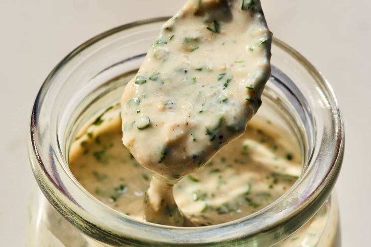 a spoon full of cheese sauce in a jar