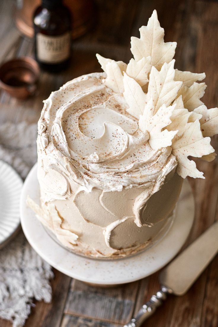 a cake with frosting and leaves on top sitting on a plate next to a bottle