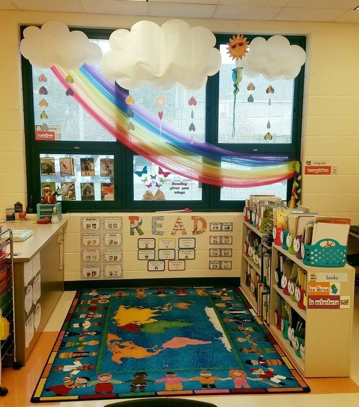 a classroom with a rainbow rug and bookshelves in front of the window that reads read