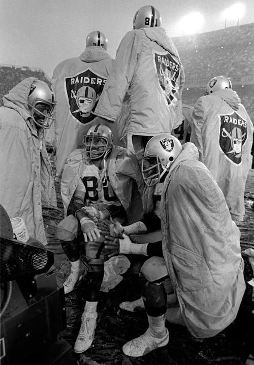 a group of football players standing around each other on a field in front of an audience