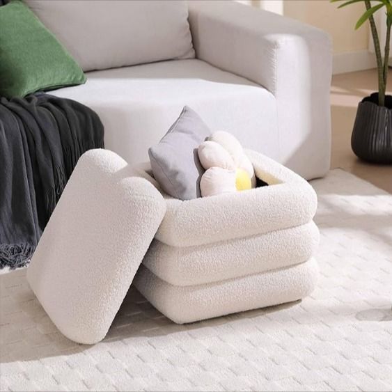 a pile of folded towels sitting on top of a white rug next to a couch