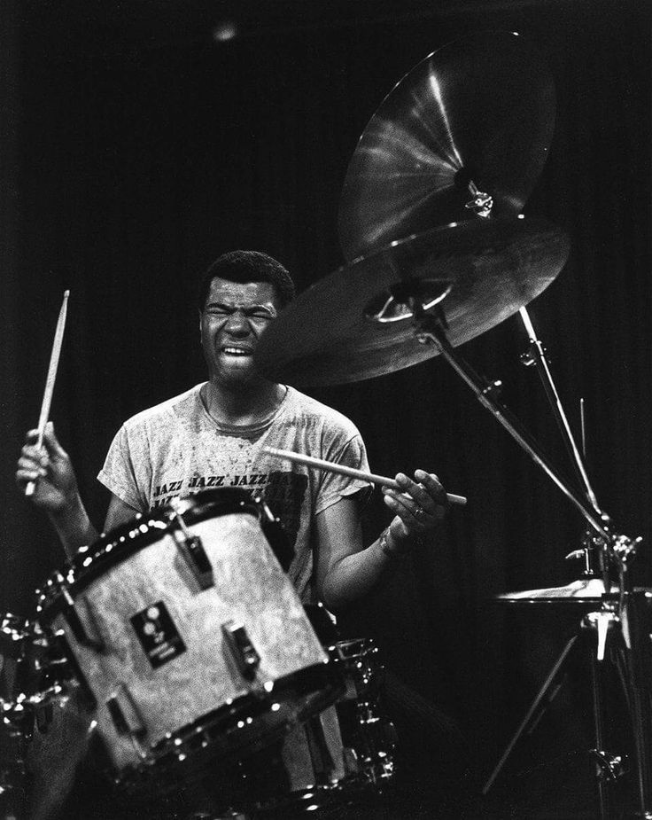 a black and white photo of a man playing drums