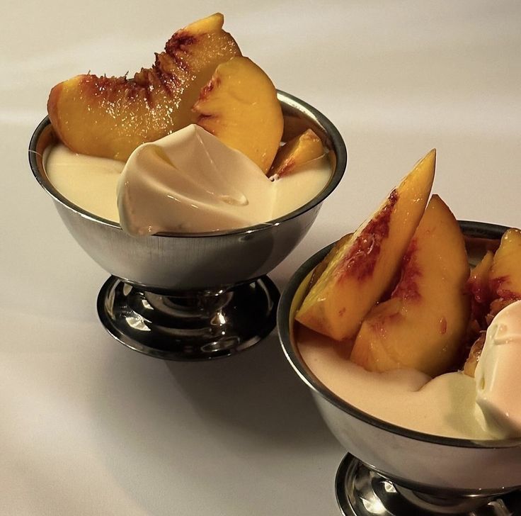 two bowls filled with ice cream and sliced peaches on top of eachother