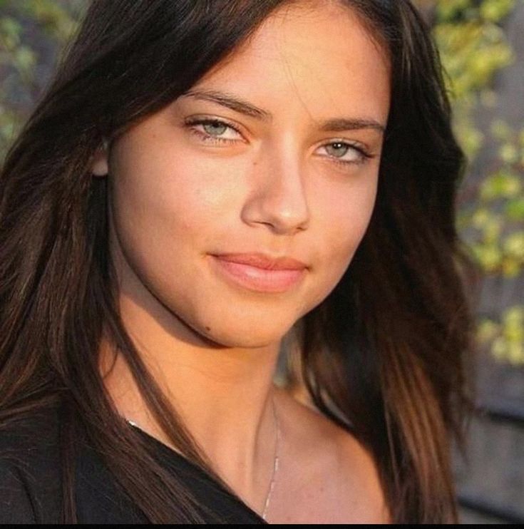 a close up of a person with long hair and brown eyes wearing a black shirt