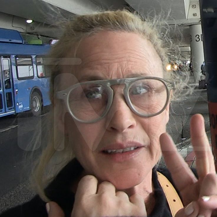 an older woman wearing glasses and making the peace sign with her hand while standing in front of a bus