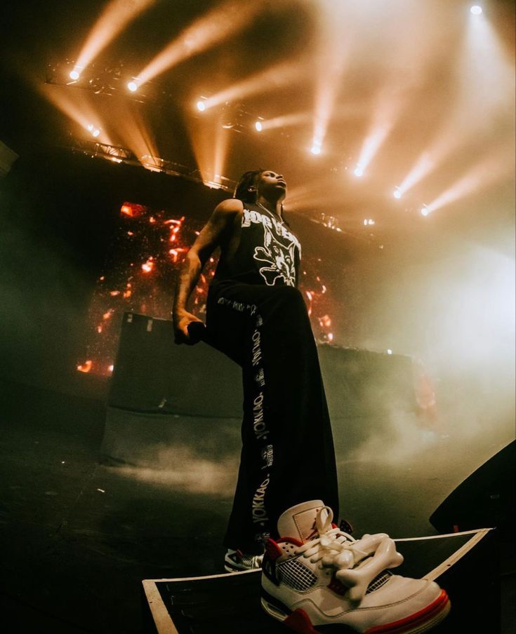 a man standing on top of a stage next to a pair of shoes