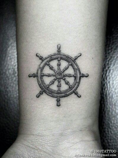 a black and white photo of a ship wheel tattoo