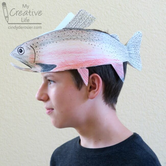 a young man wearing a paper fish hat