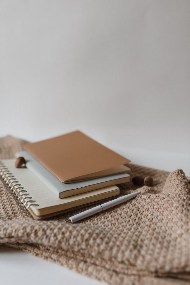 three notebooks are sitting on top of a sweater