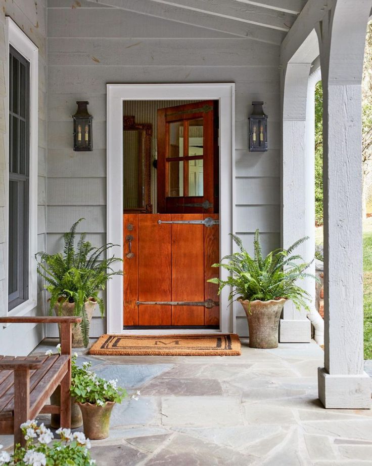 a wooden door sitting on the side of a house next to two potted plants