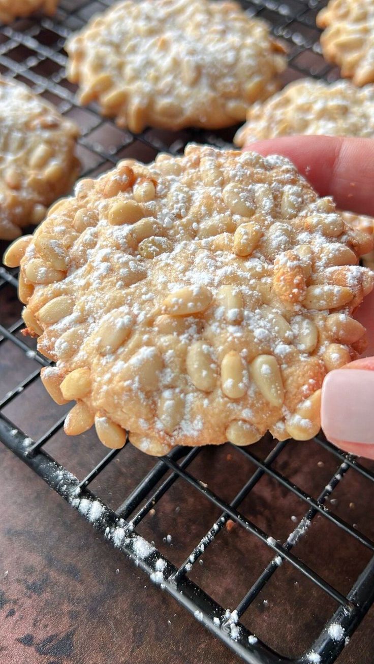 a person holding up a cookie on a cooling rack