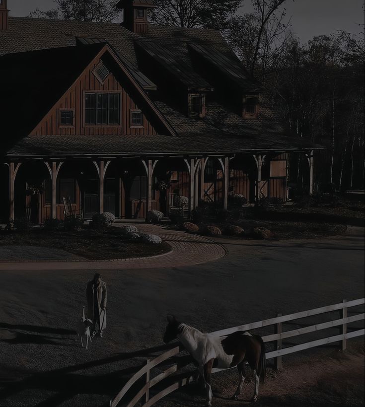 two horses standing in front of a large house