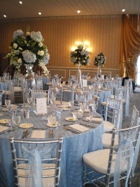 the tables are set up for a formal function with blue linens and white flowers