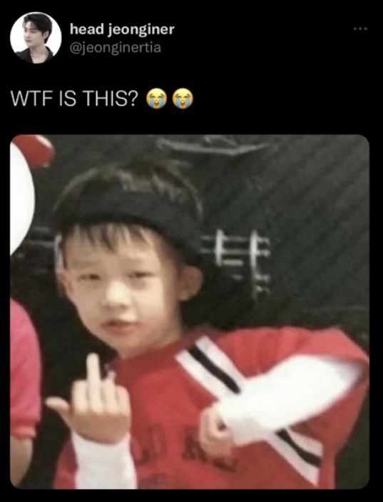 a young boy wearing a red shirt and black hat with his hand up in the air