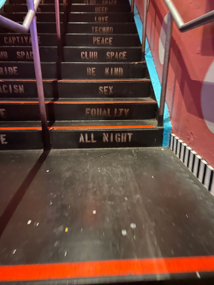 some stairs with writing on them in an area that looks like it has been painted red and blue