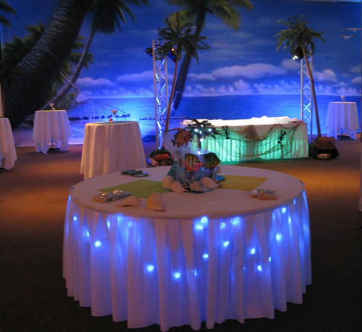 a round table with lights on it in front of palm trees and an ocean backdrop