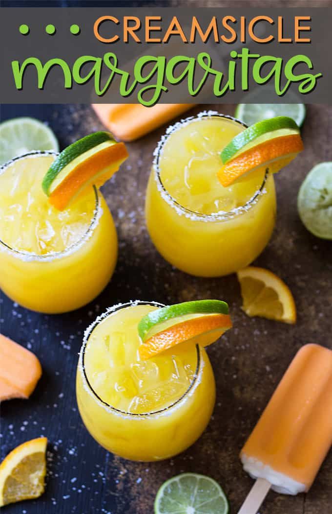 two glasses filled with orange margaritas next to lime wedges and an ice lolly