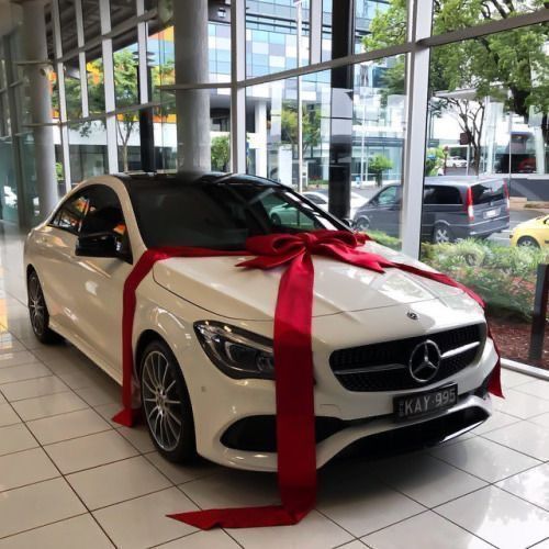 a white car with a red ribbon tied around it's hood in a showroom