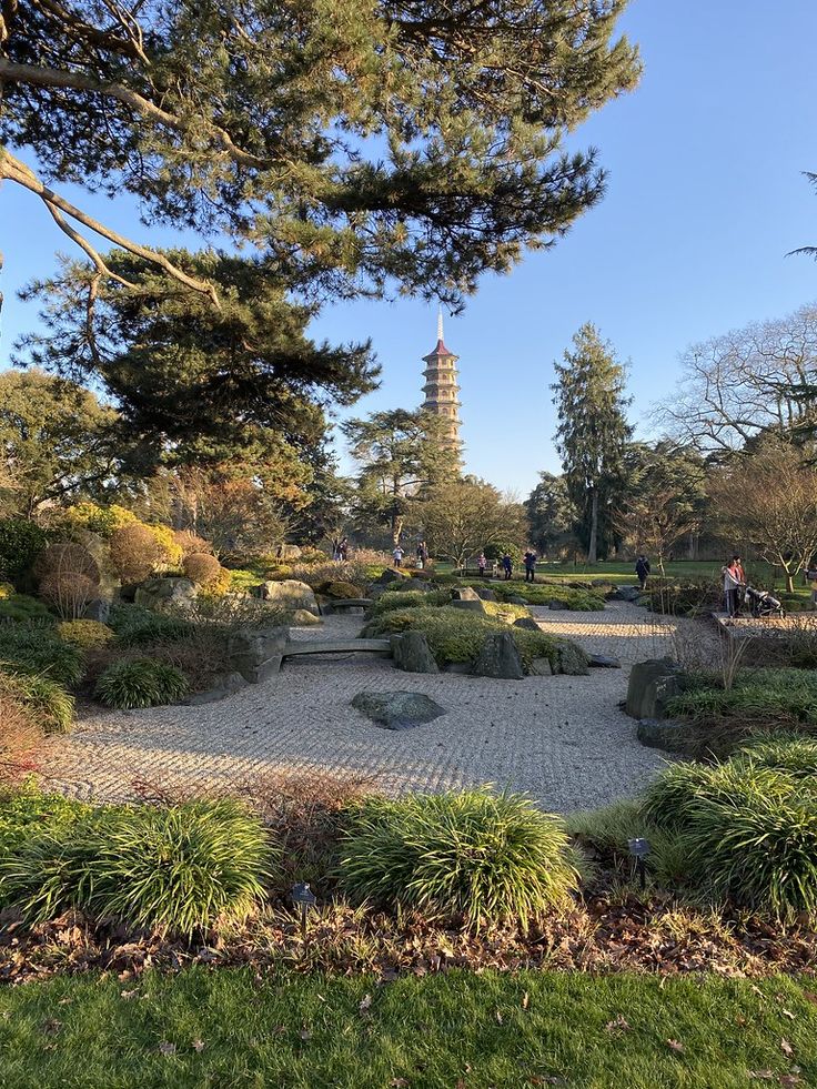 a stone path in the middle of a grassy area with trees and bushes around it