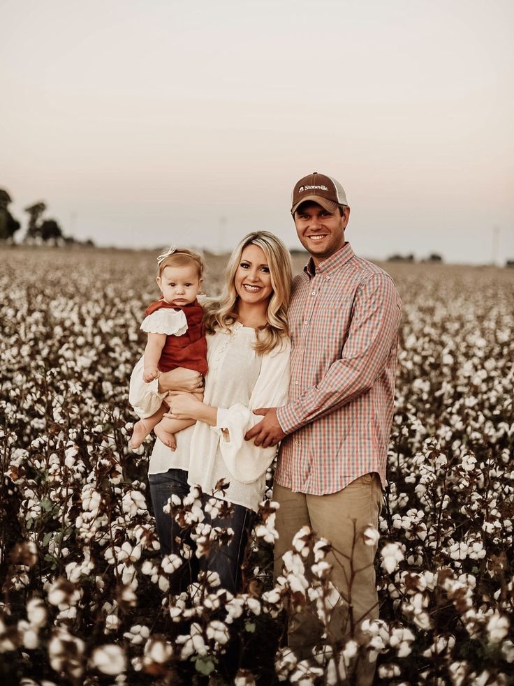 a man, woman and child standing in a field of cotton